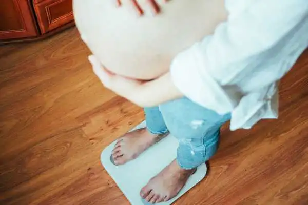 Image of woman weighing herself and experiencing weight gain through pregnancy Rutherglen
